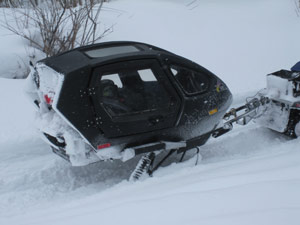 A snowmobiler towing a disabled snowmobile