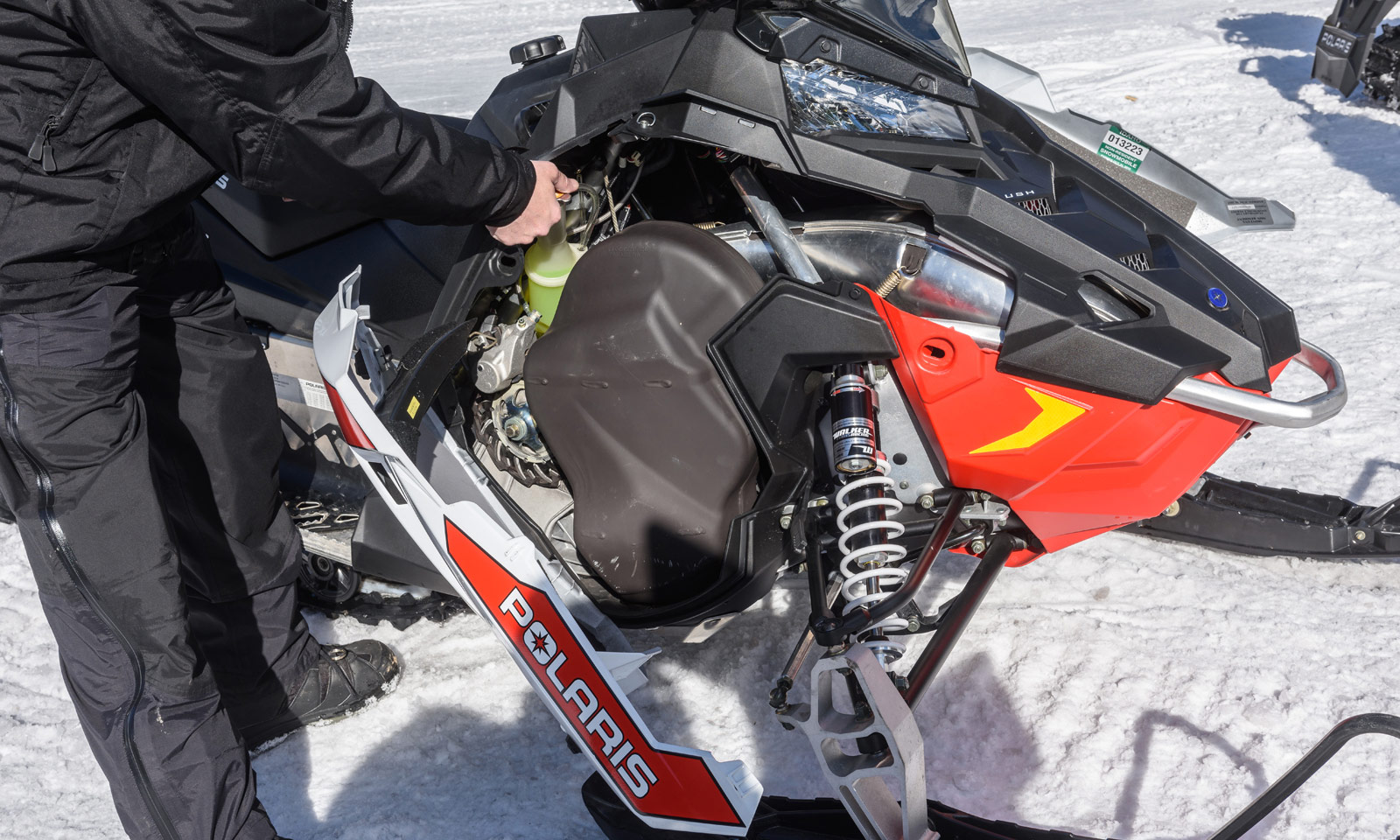 Snowmobiler checking engine fluids