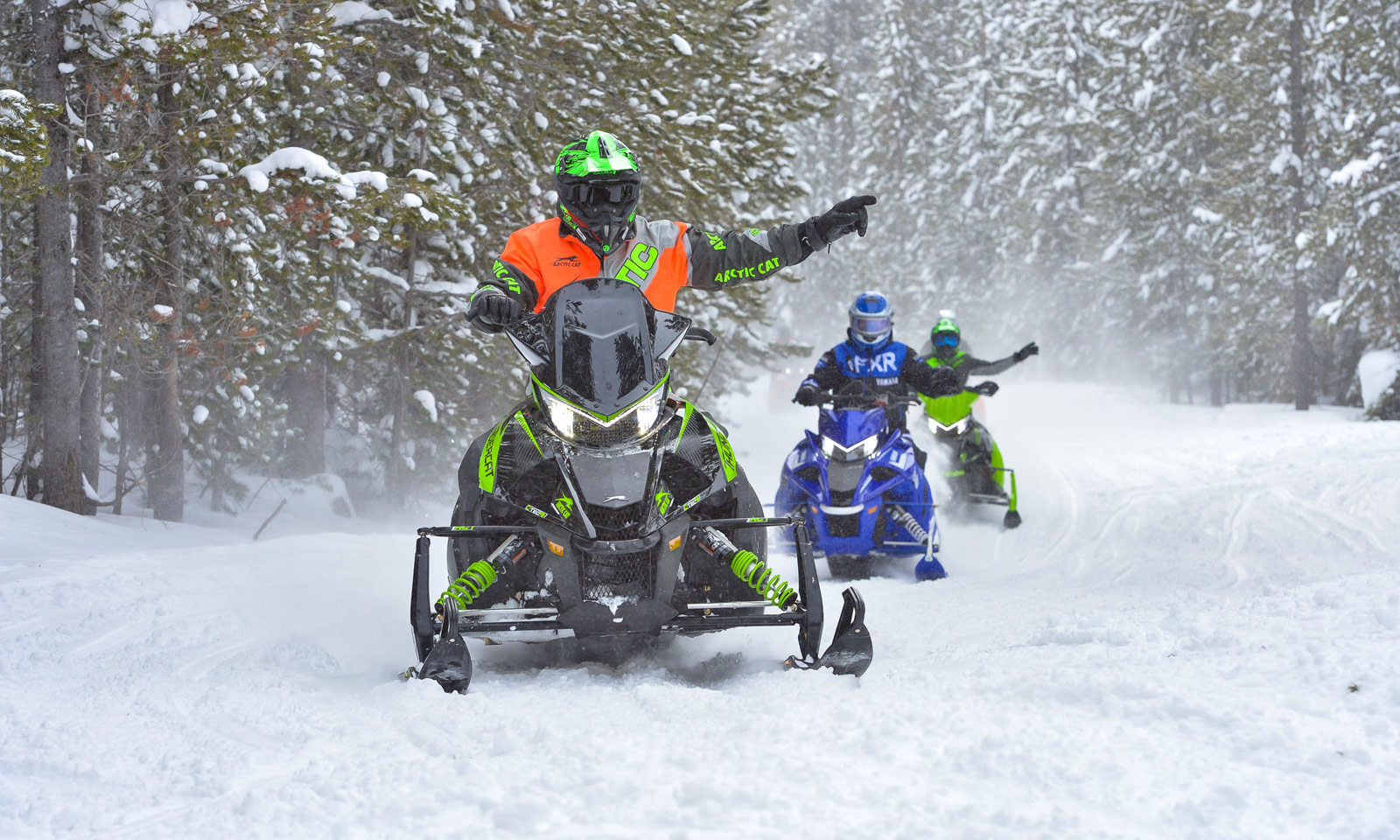 Snowmobilers showing hand signals on trail