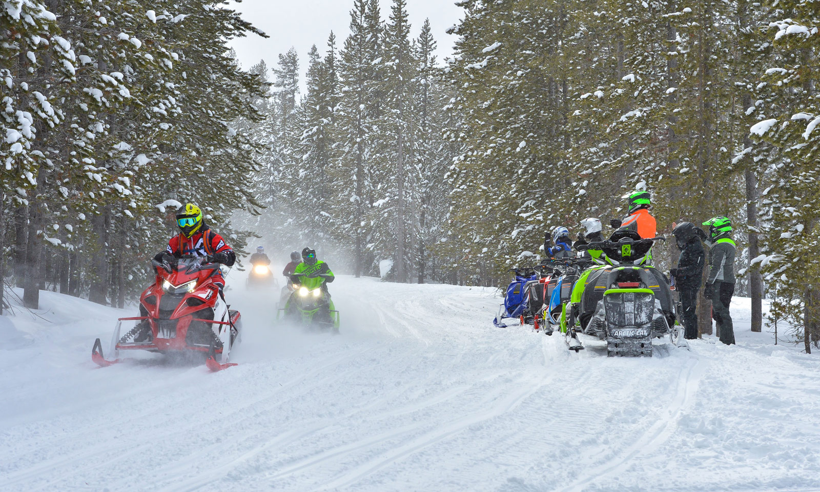 Snowmobilers riding on trail in a group