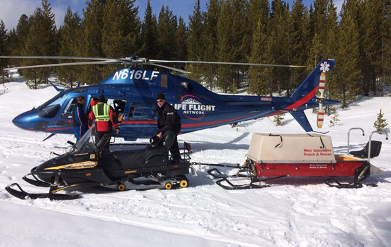 Snowmobiler being transported by helicopter