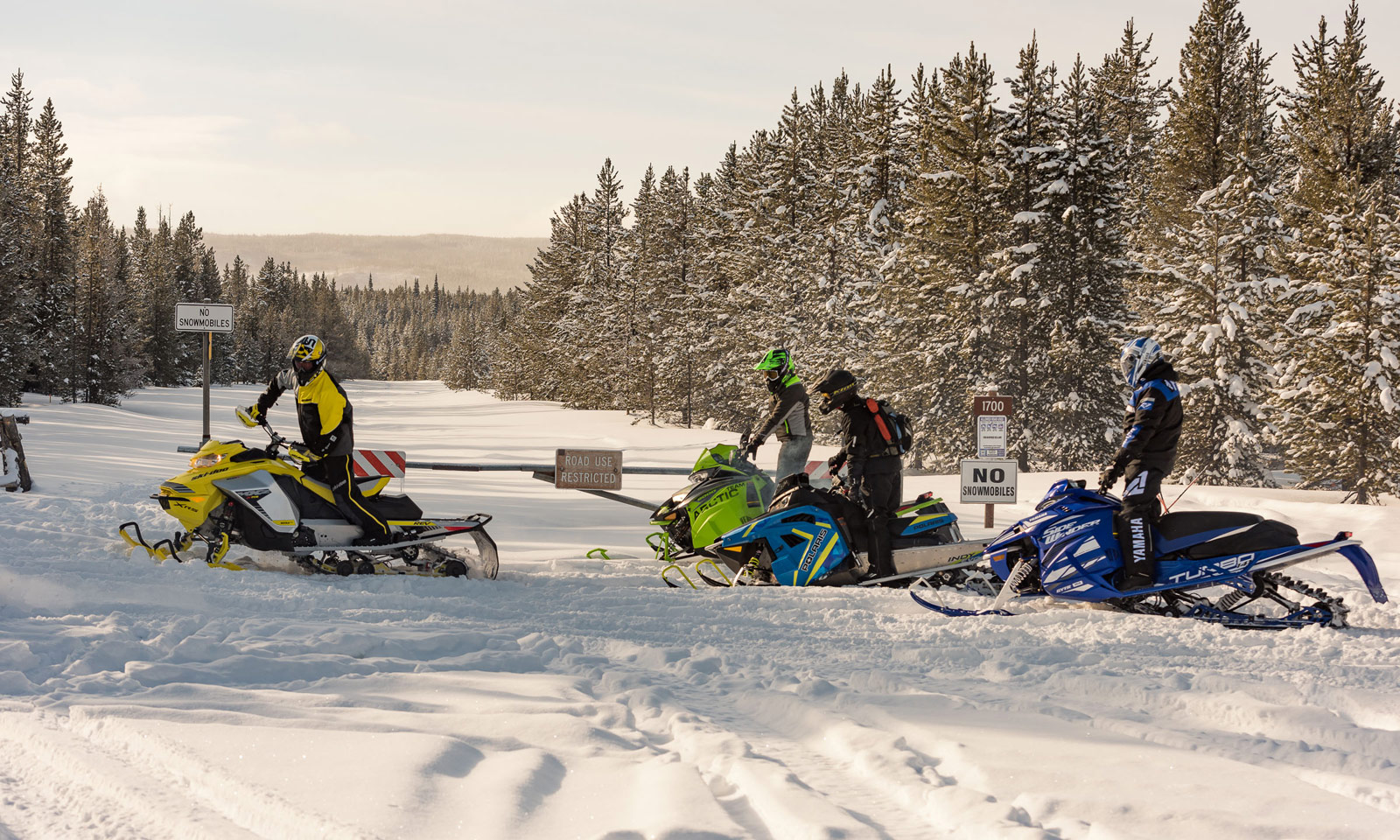 Snowmobilers on trail with sign