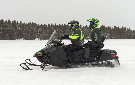 Snowmobiler riding with passenger